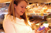 Young woman looking at products in hand from shelf